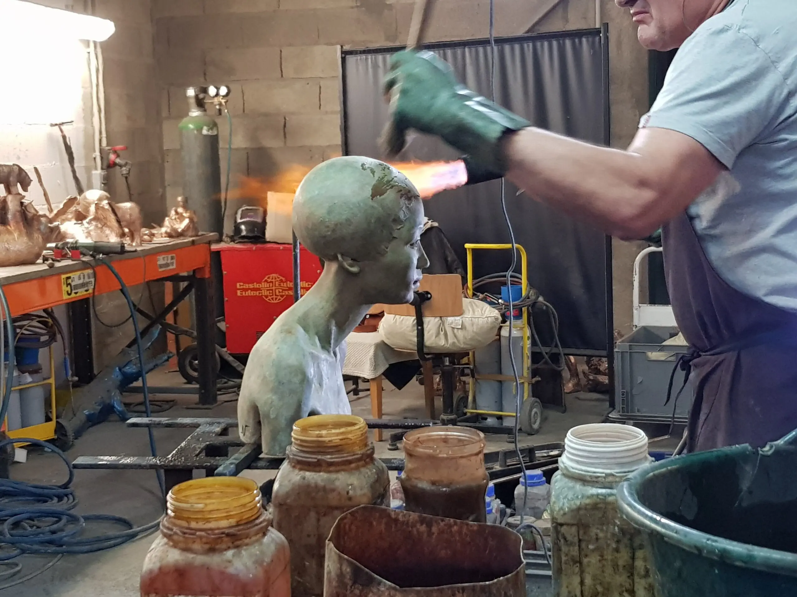 Artiste travaillant sur une sculpture en atelier.