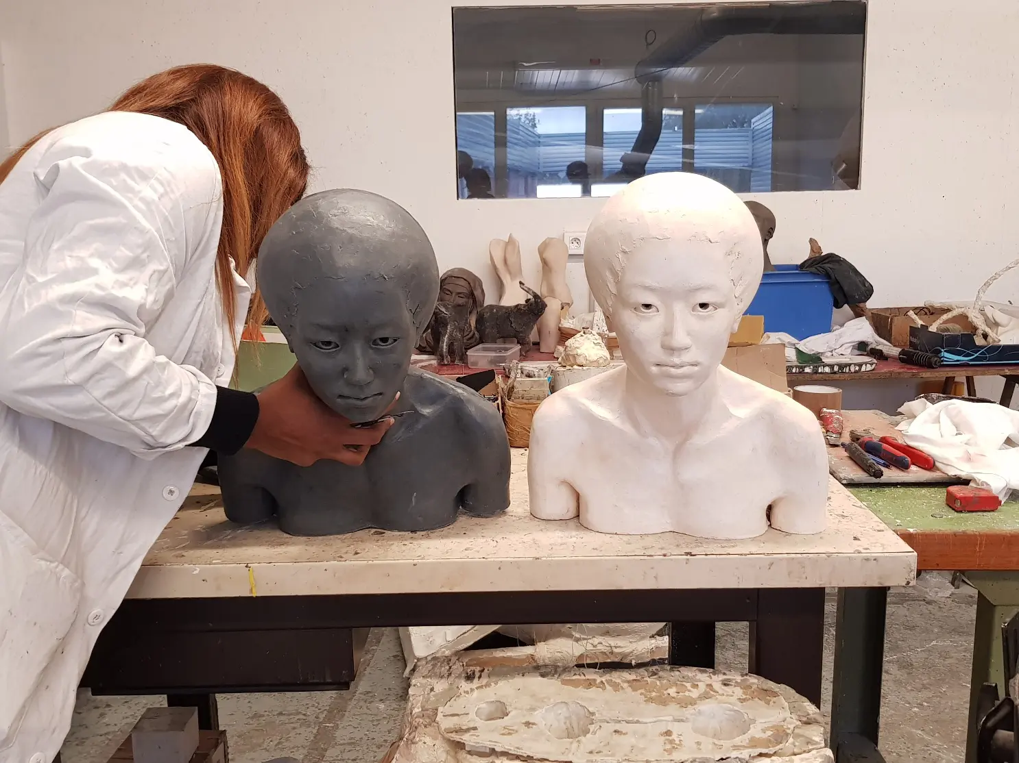 Artiste peignant deux bustes en atelier.